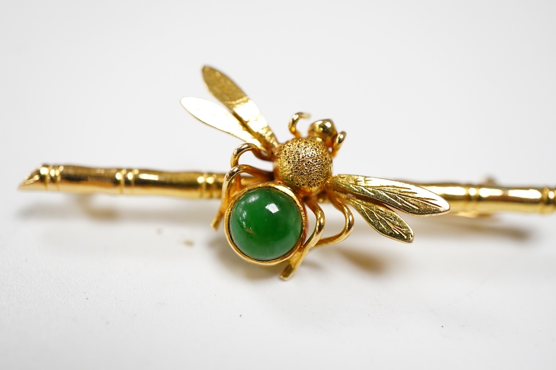 An Edwardian two colour 9ct owl bar brooch, with green cabochon eyes, 48mm, gross 2.5 grams, together with a yellow metal (stamped 20) and single stone cabochon jade set bug bar brooch, gross weight 3.7 grams.